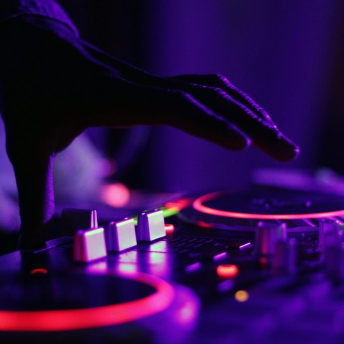 selective focus silhouette photography of man playing red-lighted DJ terminal